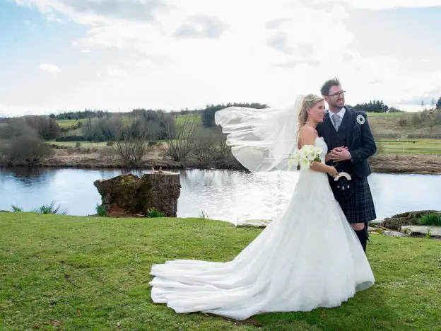 A bride and groom having their Maryculter House Hotel wedding photos in front of the river Dee