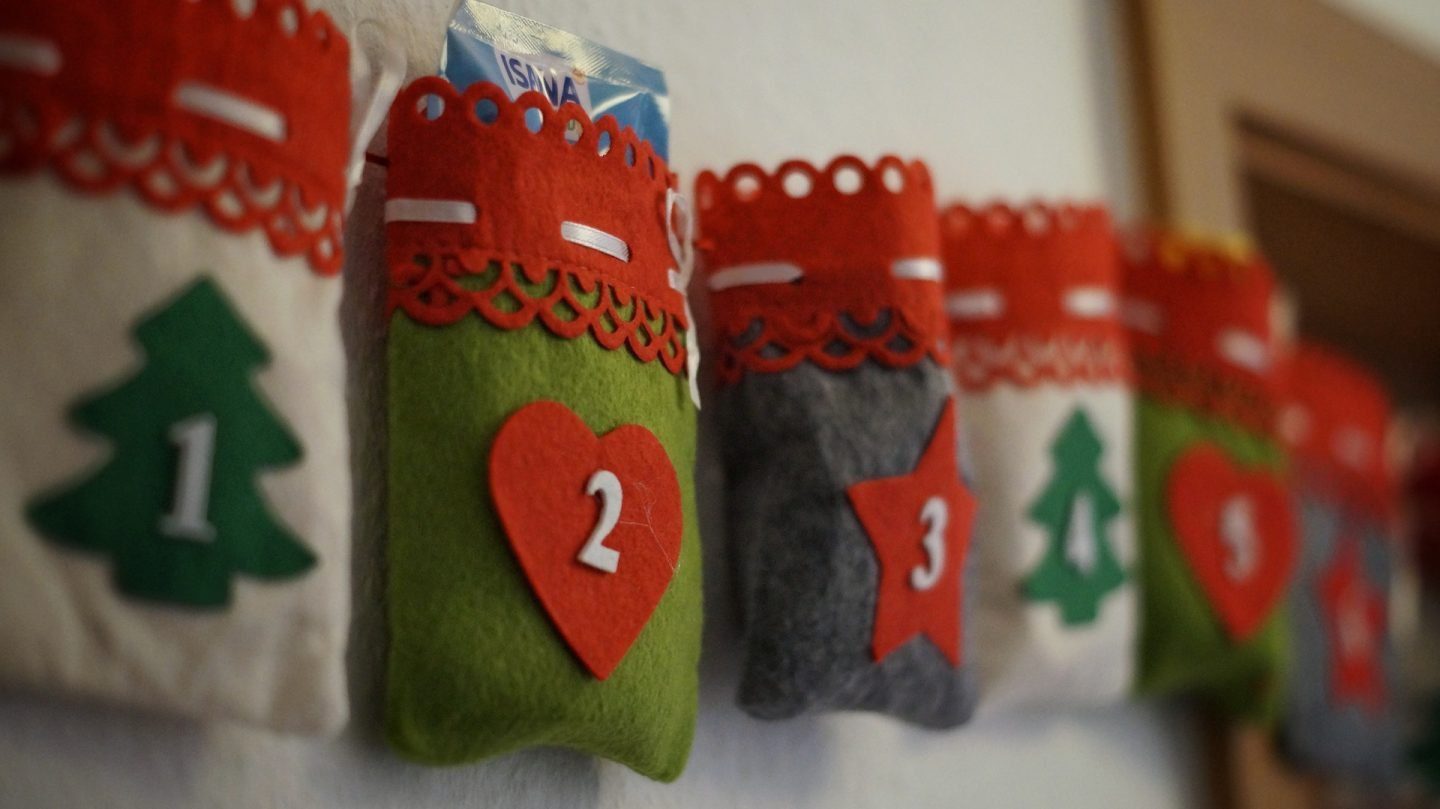 A white green and red fabric advent calendar against a white wall
