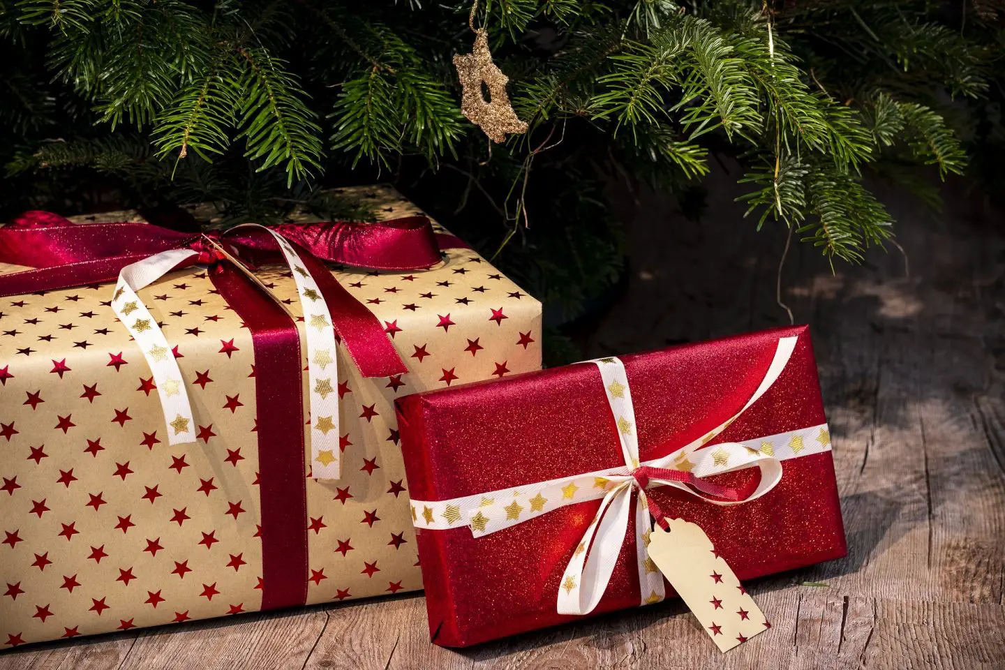2 Christmas presents under the tree wrapped in red and gold wrapping paper