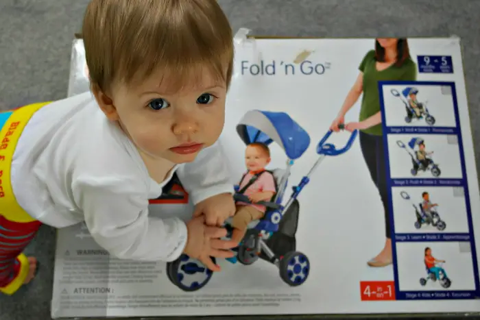 A young boy climbing on top of a Little Tikes Fold 'n' Go 5-in-1 Trike box 