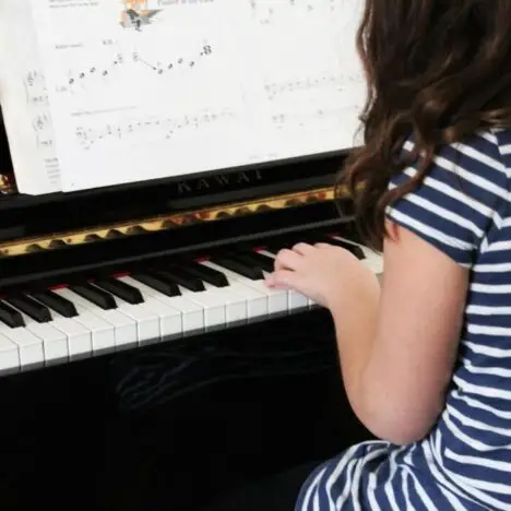A girl sitting playing a piano
