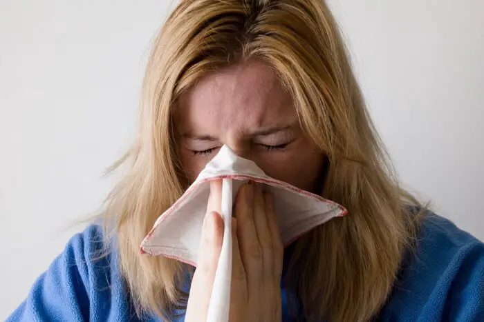 A woman sneezing into a handkerchief