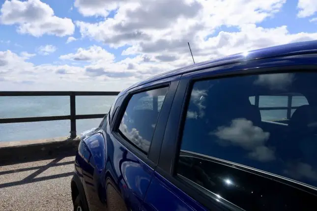 A side view of a blue Nissan Juke next to the sea
