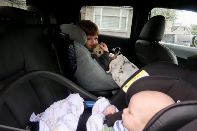 2 children in car seats in the back of a car