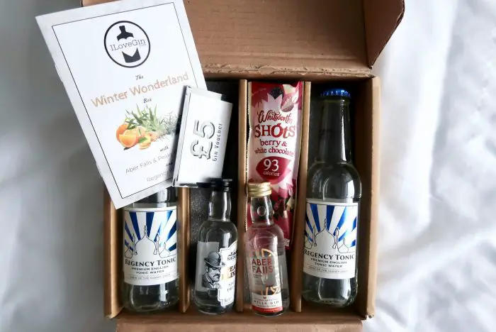 A subscription box containing two miniature bottles of gin, two bottles of tonic and a snack
