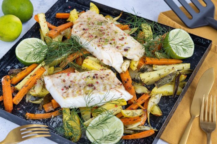 A baking tray with roasted vegetables and fish on it