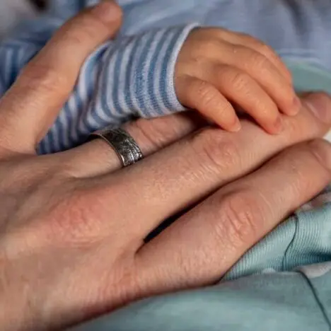 A mans hand with a newborn hand on top