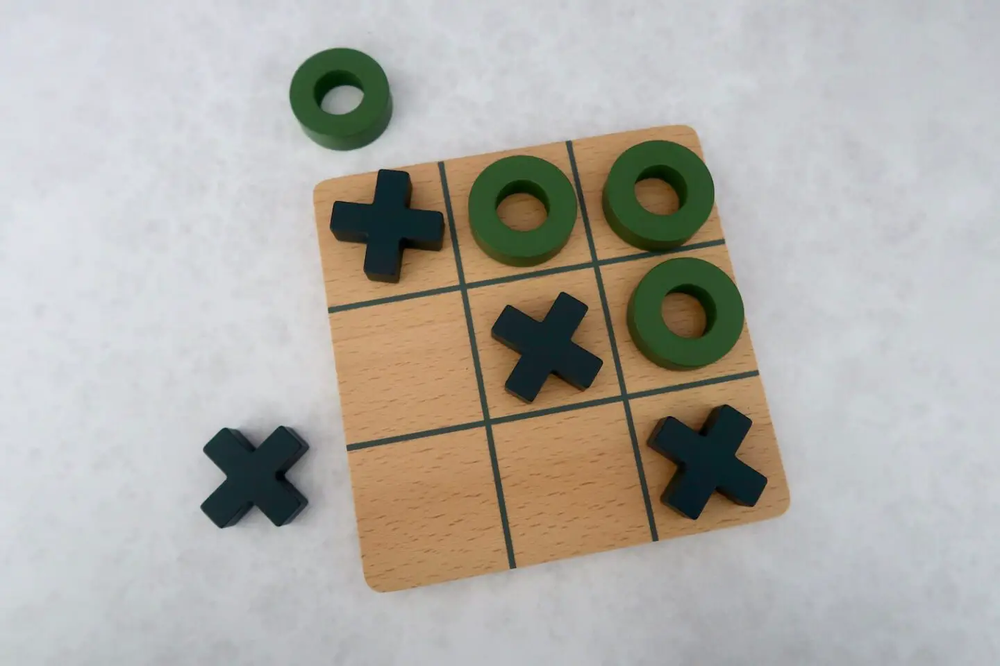 A wooden tic-tac-tie board with wooden noughts and crosses