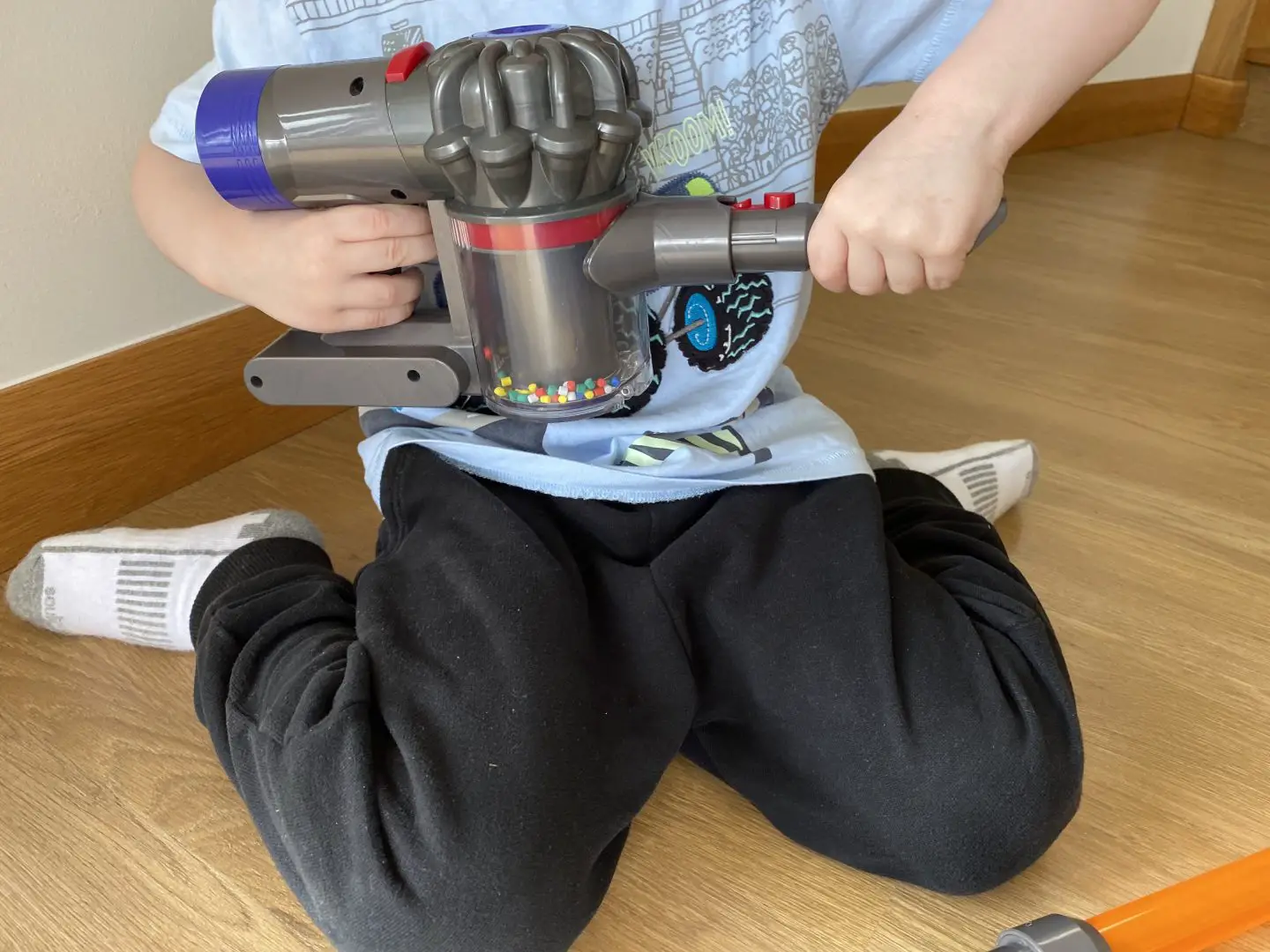 A boy playing with a toy vacuum cleaner