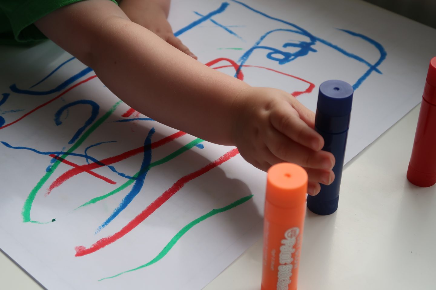 A toddlers hand reaching for a paint stick
