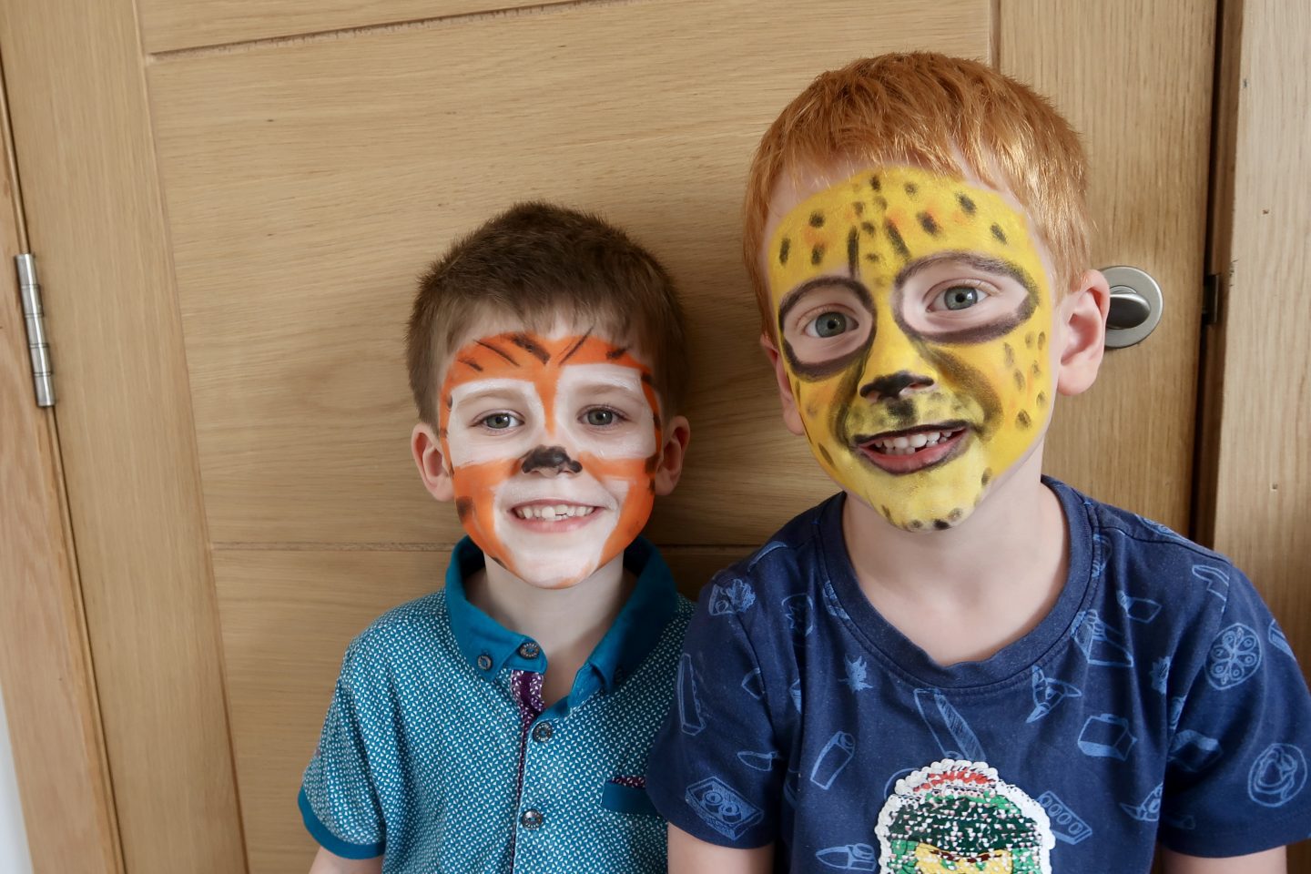 2 boys with their faces painted, one as a tiger and one as a cheetah