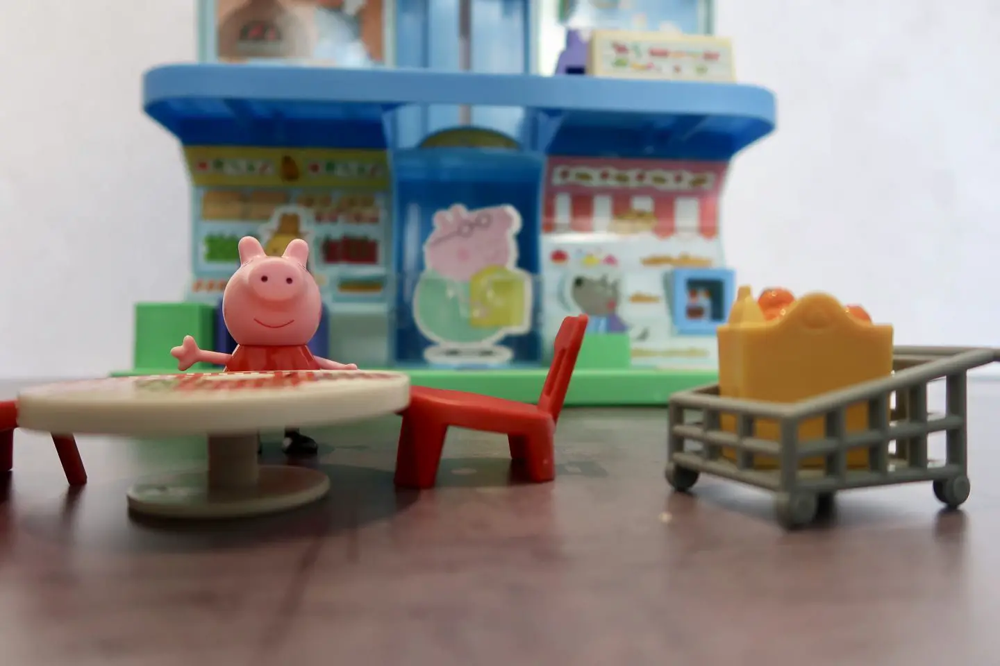 A Peppa Pig figure at a table in front of a Shopping Centre playset