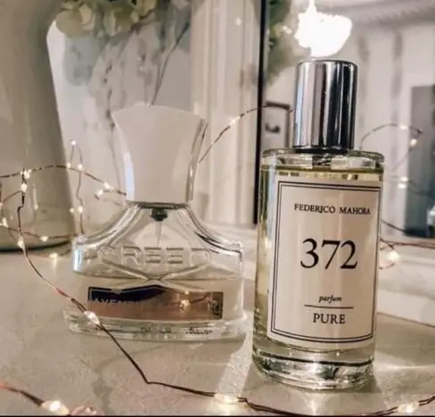 A bottle of Creed, Aventus for her perfume and FM 372 on a dressing table with fairy lights