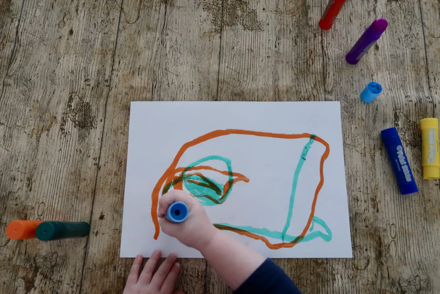 A top down view of a painting a child is making using paint sticks