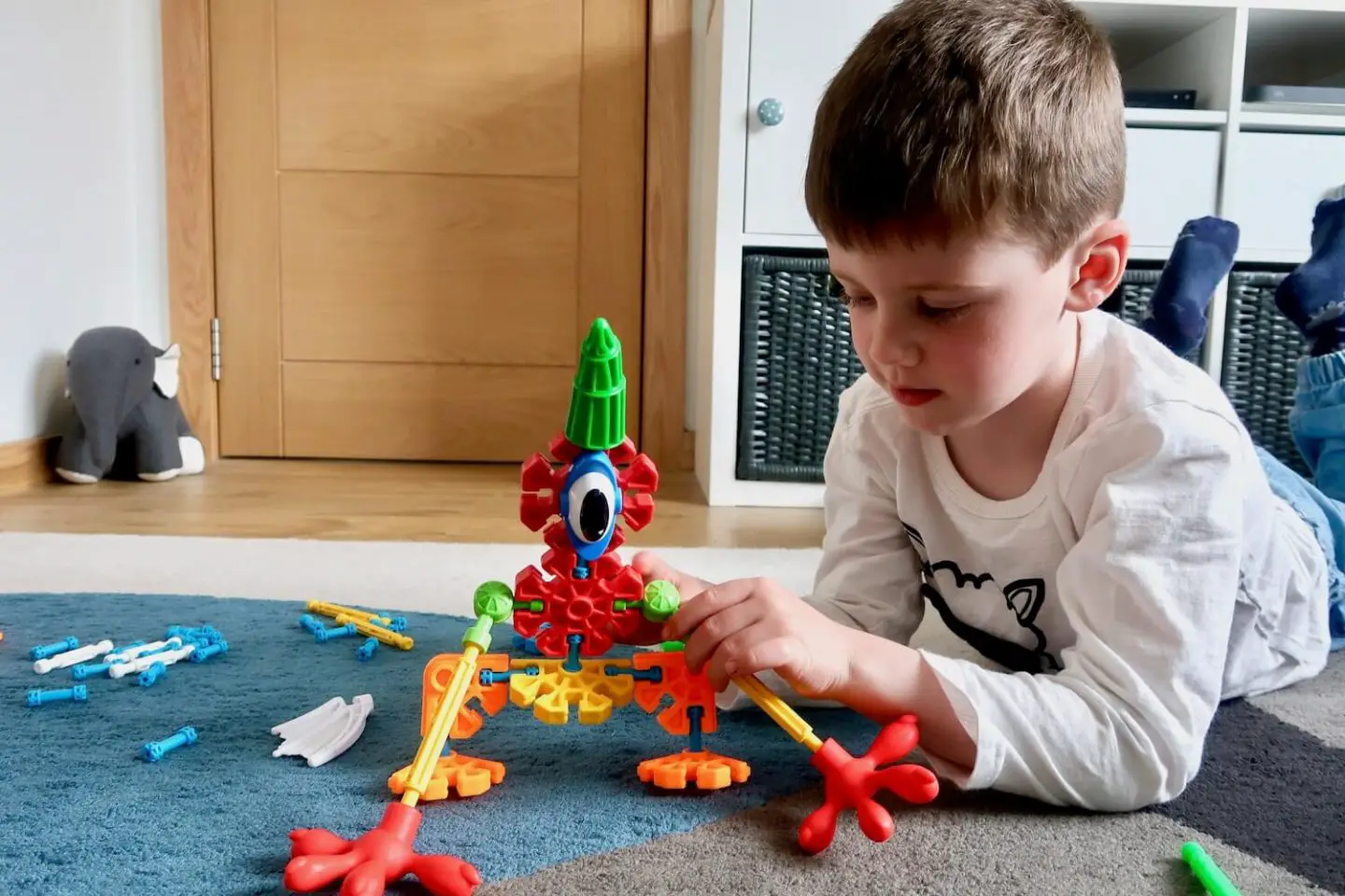 A young boy holding the leg of a K'Nex creature he has made