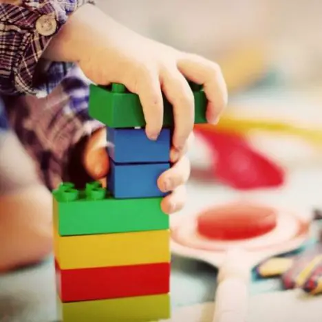 A child's hands stacking multicoloured Duplo blocks