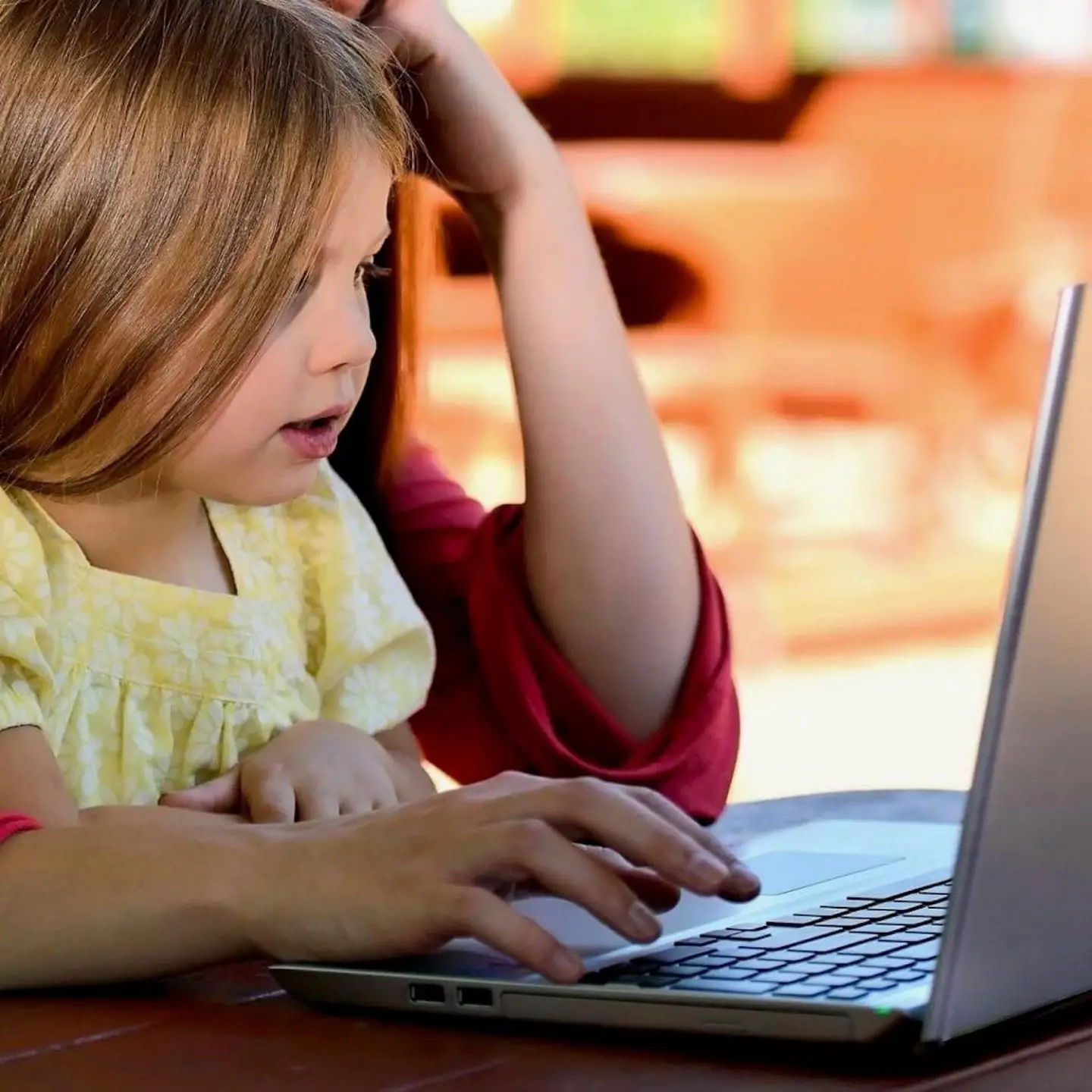 A little girl sitting looking at a laptop
