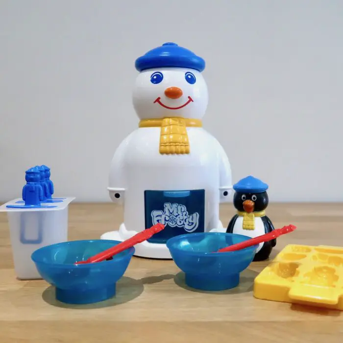 The contents of a Mr Frosty box. A snowman machine, ice lolly moulds, 2 blue bowls, 2 red spoons, a penguin flavour dispenser and an ice cube tray