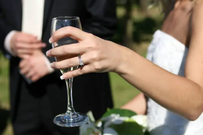A brides hand holding a champagne glass
