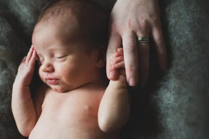 A newborn baby holding a finger.