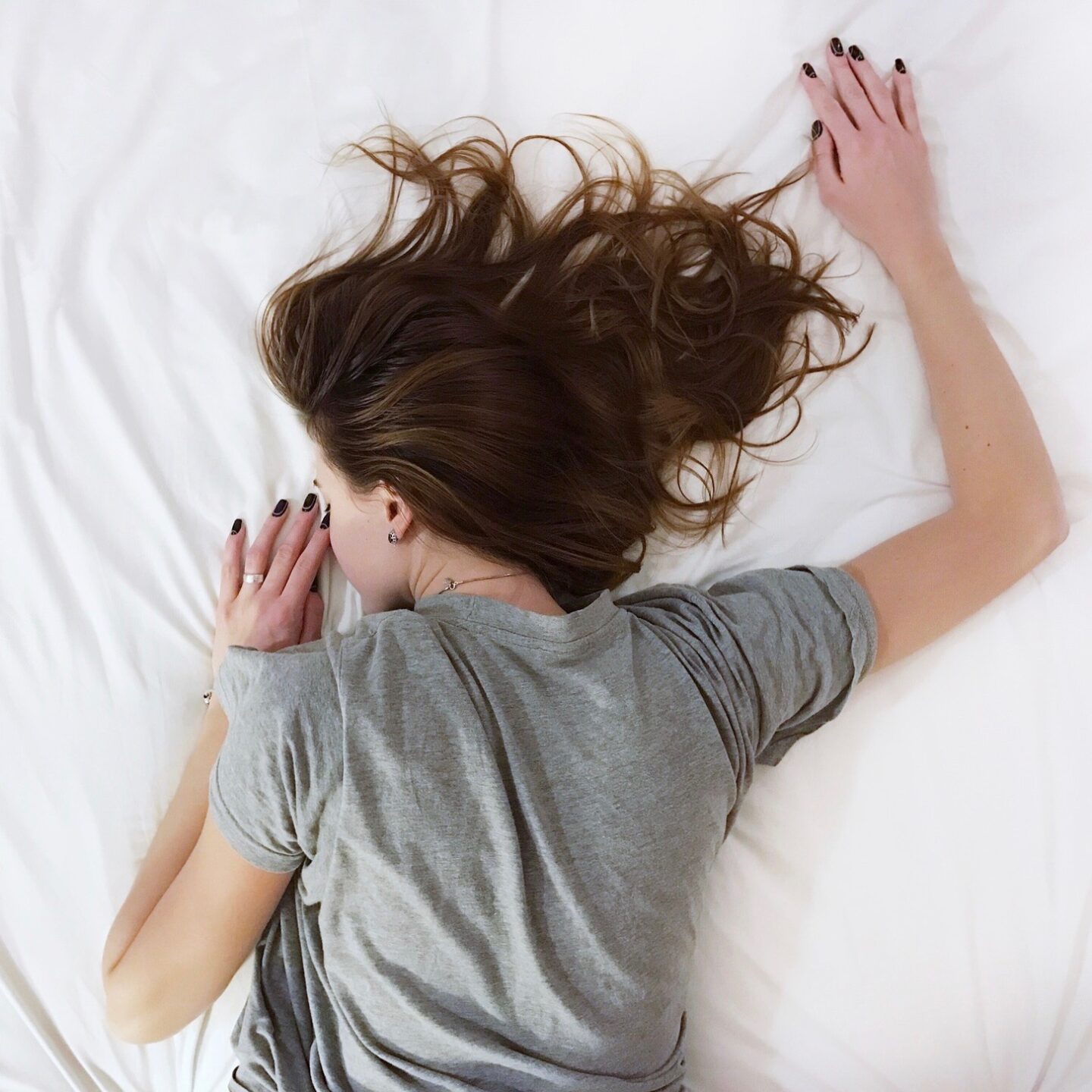 A woman lying facedown on a white sheet asleep
