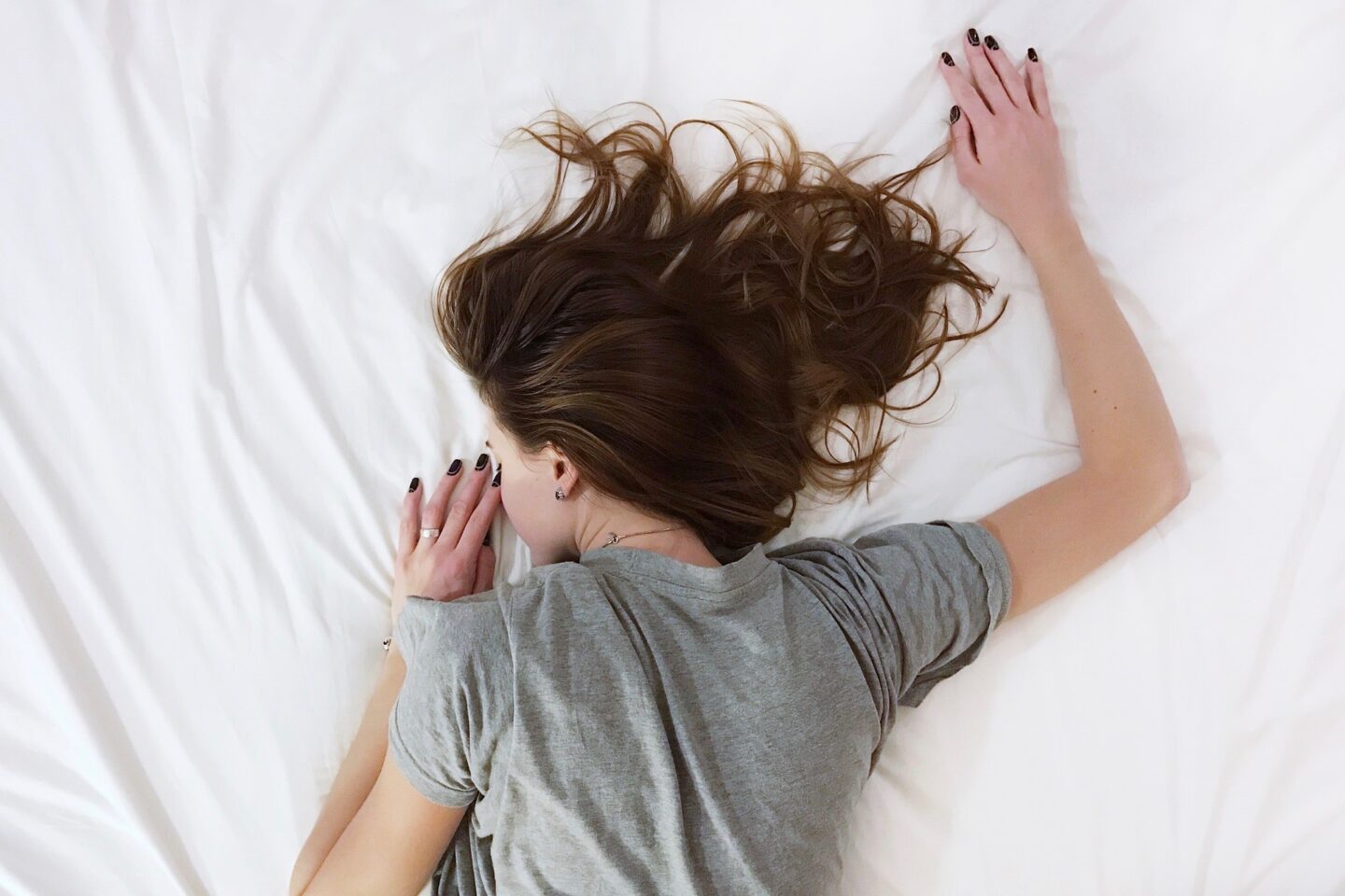 A woman lying facedown on a white sheet asleep