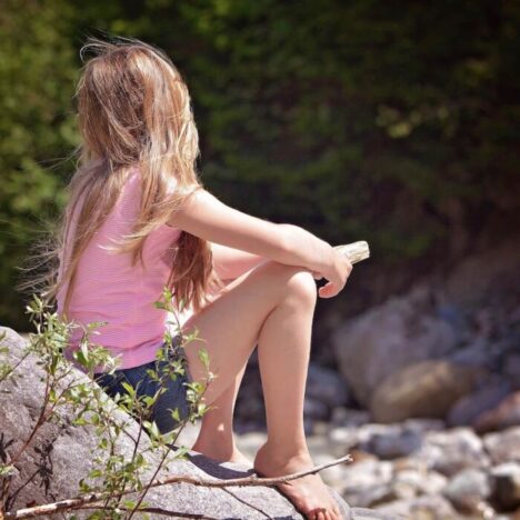 A girl sitting on a rock and looking away from the camera