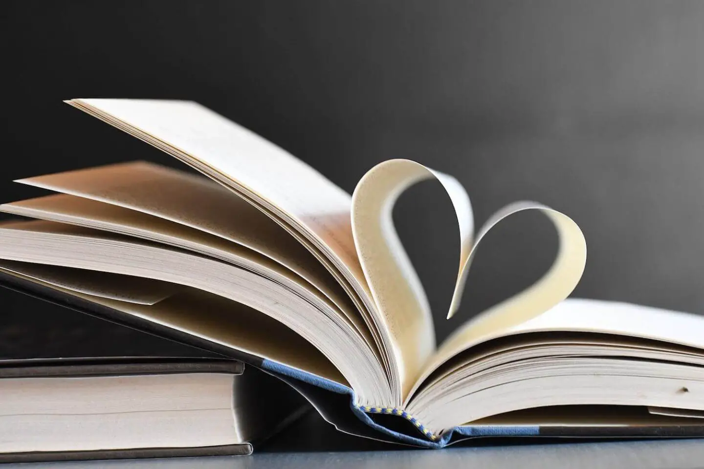 A book open, with 2 pages folding down towards each other to make a heart