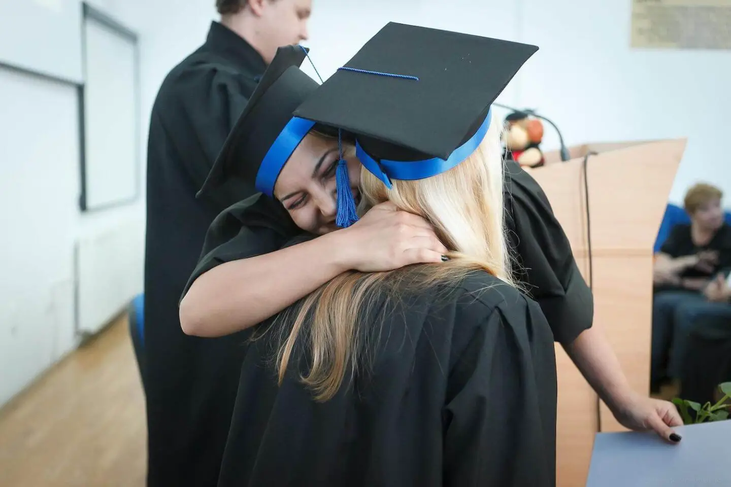 2 girls hugging in graduation caps and gowns