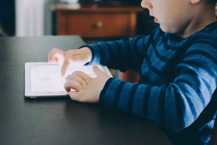 A child sitting at a table and playing on a tablet