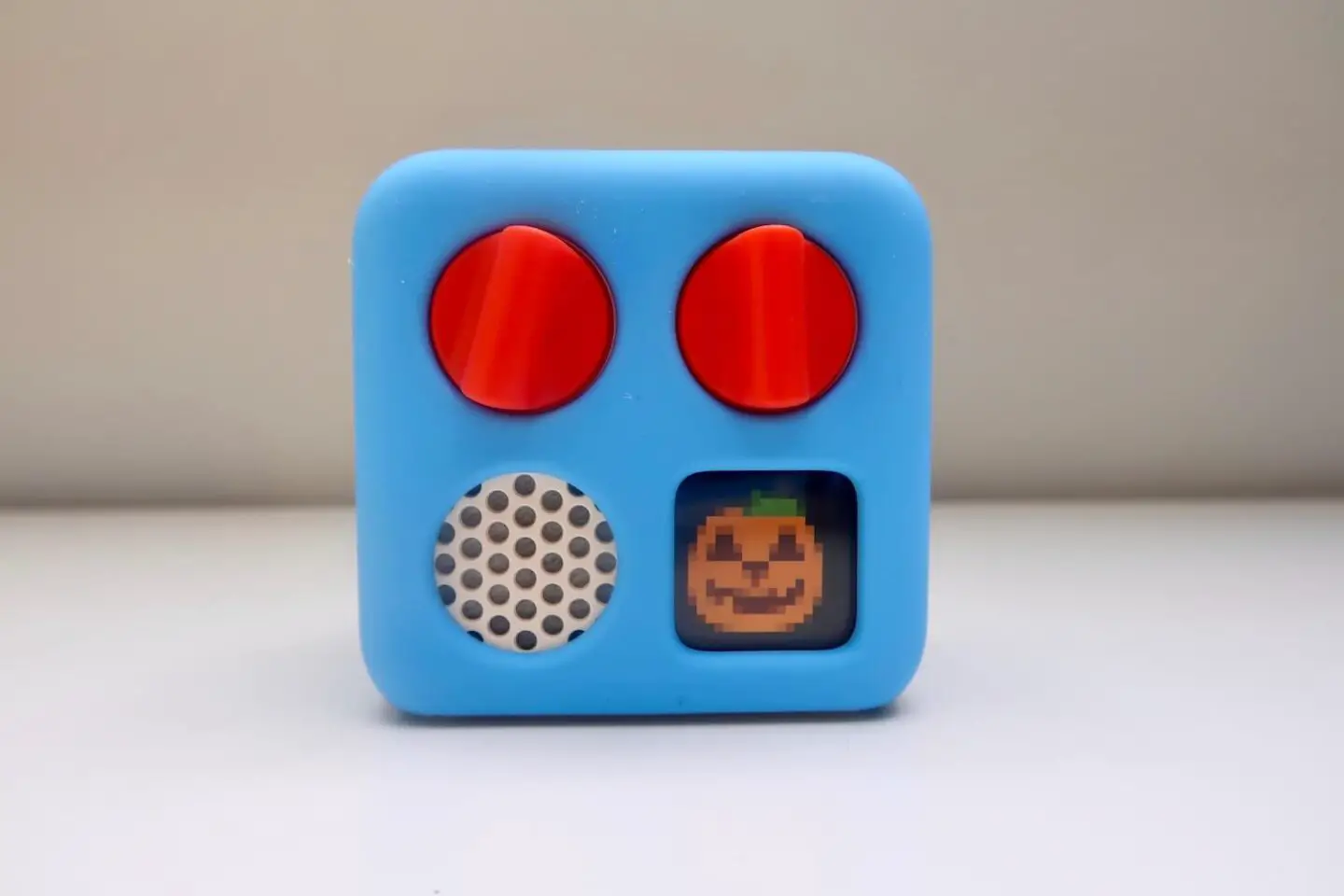 A Yoto mini wearing a blue adventure jacket. The mini screen is showing a pumpkin