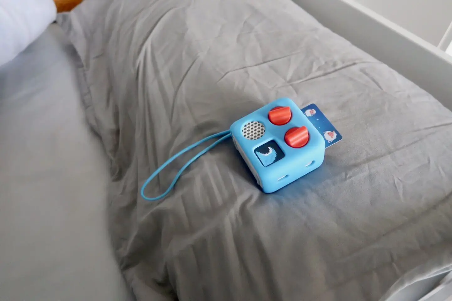 A Yoto player lying on a grey pillow on a bed