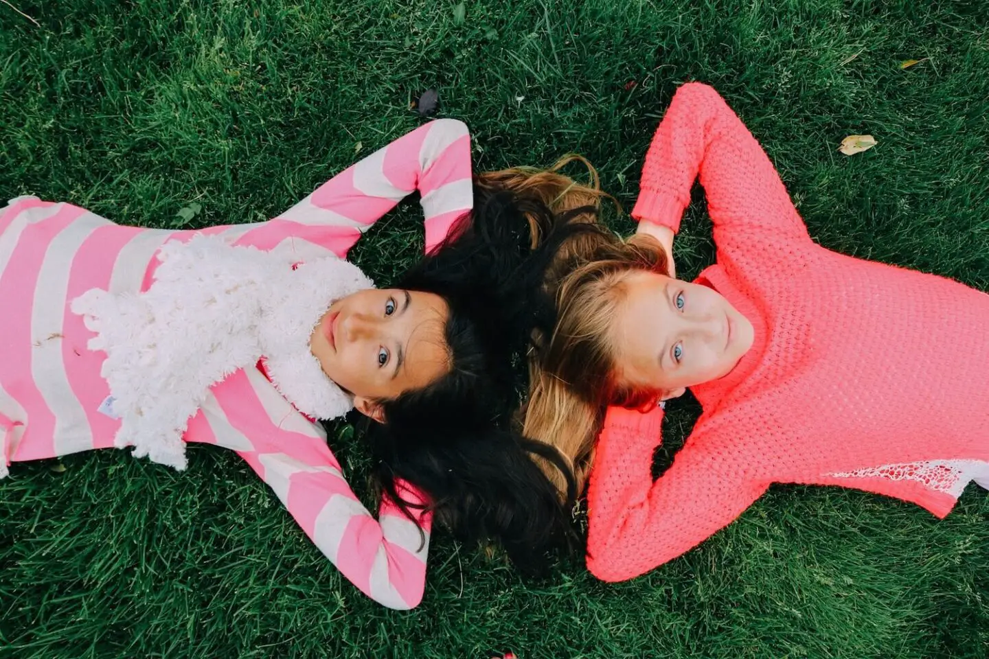 2 teenage girls lying on the grass with their arms behind their heads