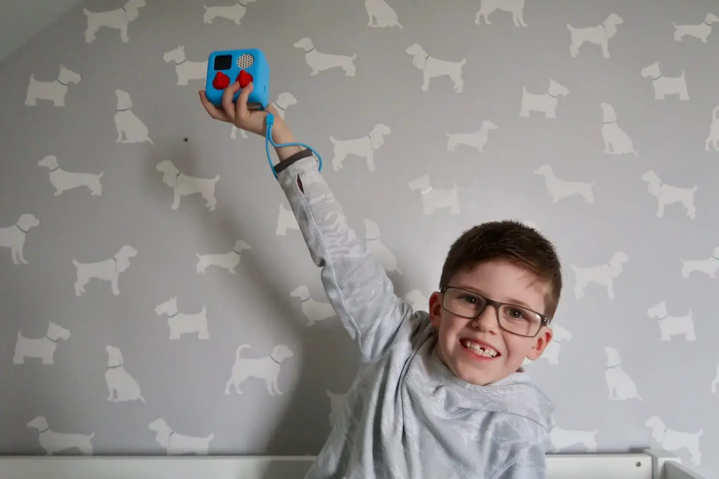 A boy holding a Yoto mini up above his head