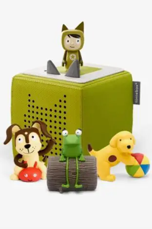 A green tonie box with Tonie characters on and around it. There is a frog on a log, spot the dog and a brown and cream dog