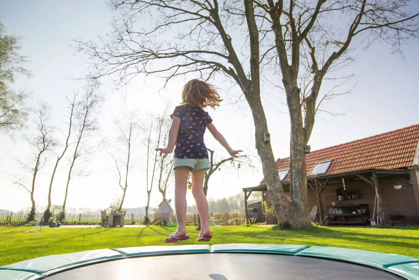 A girl jumping on a trampoline outside