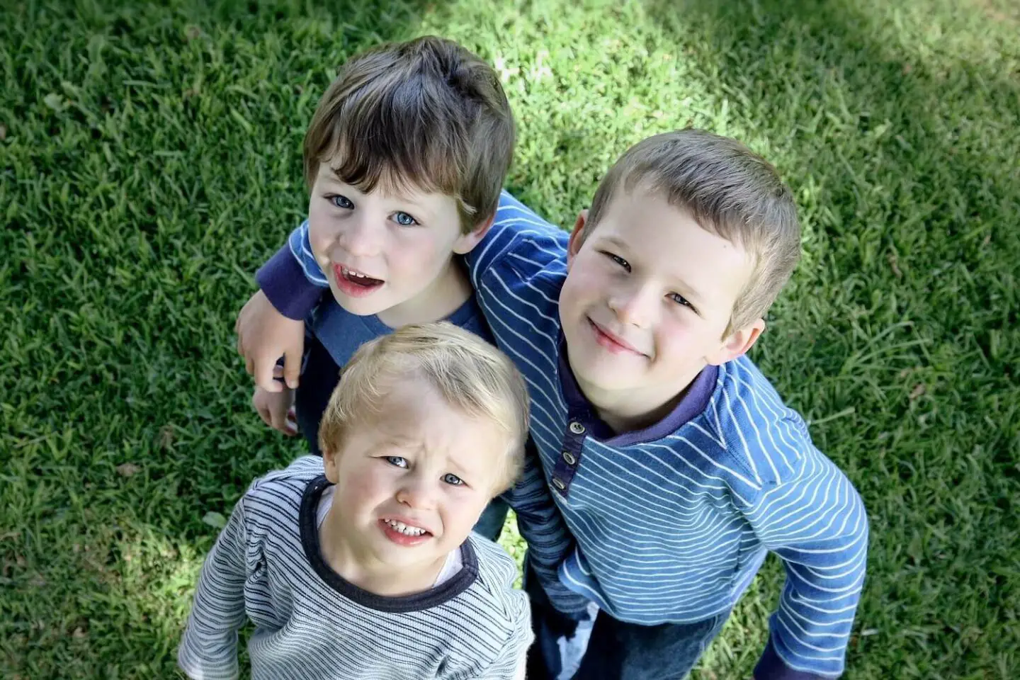 3 brother's looking up at the camera and smiling