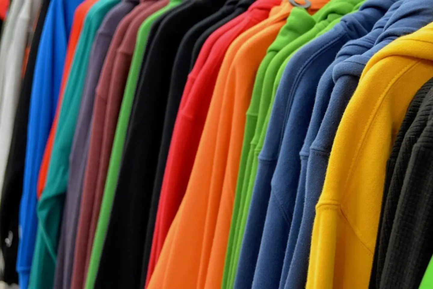 Sweatshirts in an array of rainbow colours, hanging up.