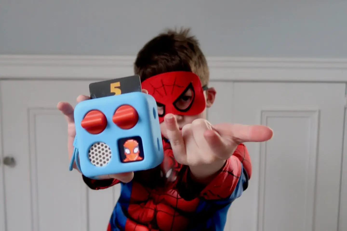 A boy dressed as Spiderman holding out a Yoto mini