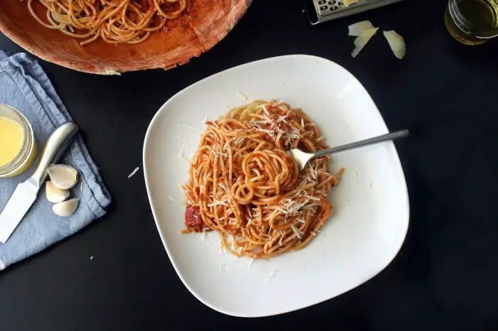 A large plate of spaghetti bolognese on a black table