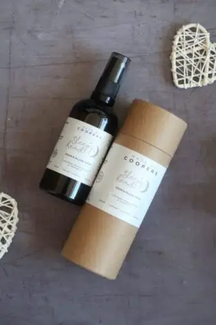 A bottle of room and pillow spray next to a cardboard storage tube